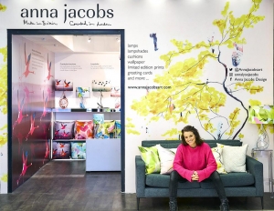 website cover   Anna Jacobs sitting on the sofa outside her new shop 1t 196 Tottenham Court Road   wearing pink jumper 2048x
