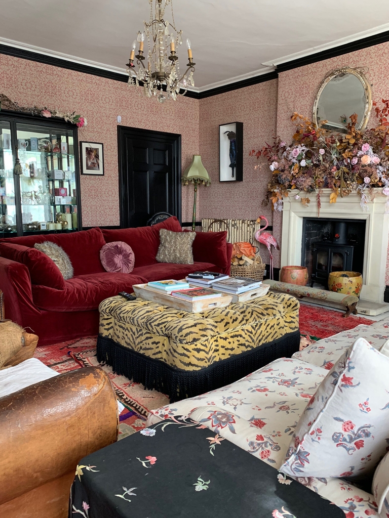 home of pearl lowe's living room with red velvet sofa, robert kime wallpaper and tiger print footstool