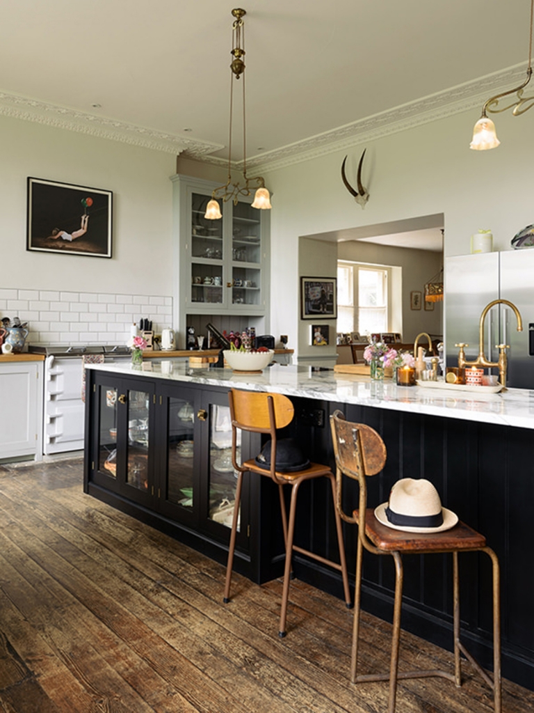 black devol kitchen with carrera marble work tops, brass taps, vintage 1930's lights, modern art, metro tlies and vintage 40's bar stools in the home of pearl lowe
