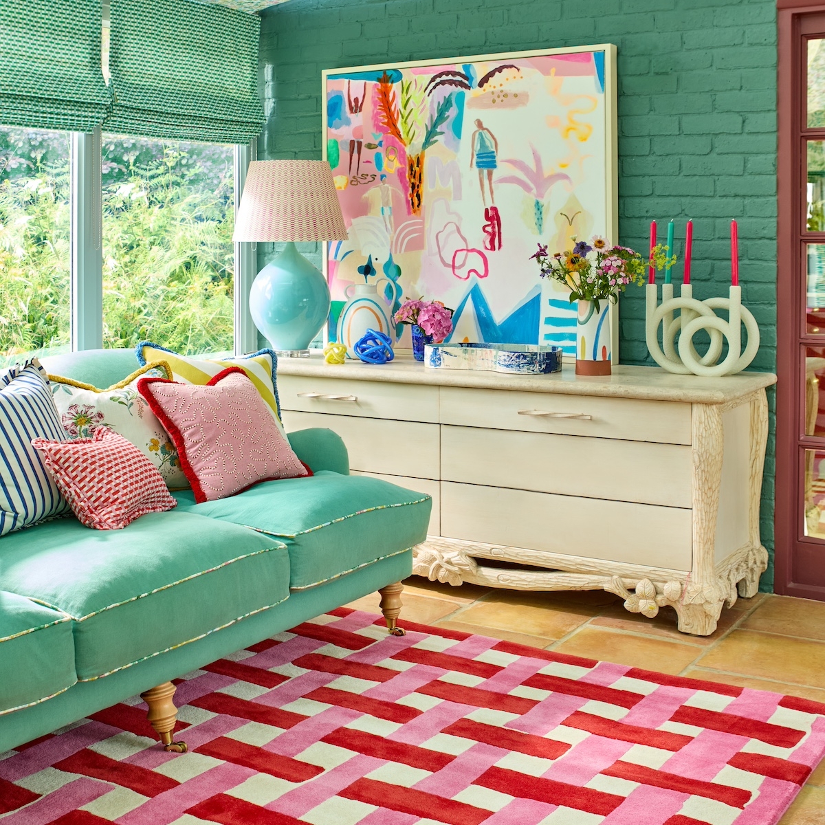 red and pink basketweave rug with green sofa in maximalist room